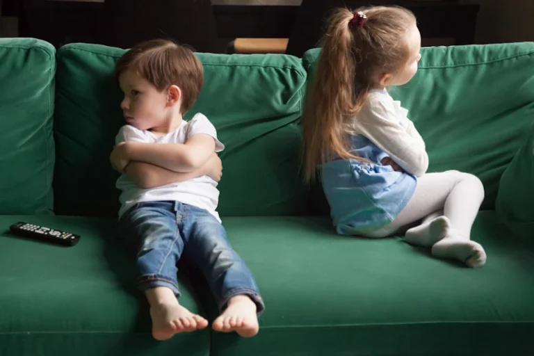 Boos jongentje en meisje van elkaar afgekeerd op de bank