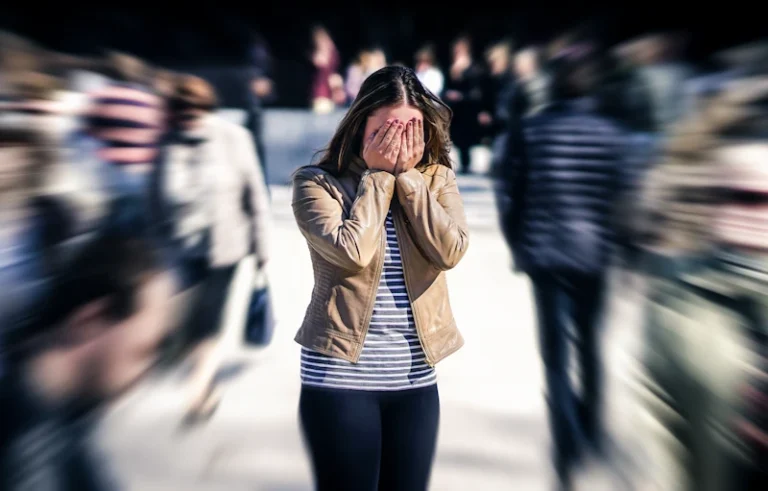 Ontredderde vrouw met handen voor haar ogen in drukke straat waar iedereen doorloopt