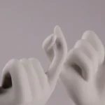 Kunstwerk van stenen handen die de pinken verbinden als symbool van beloftes.