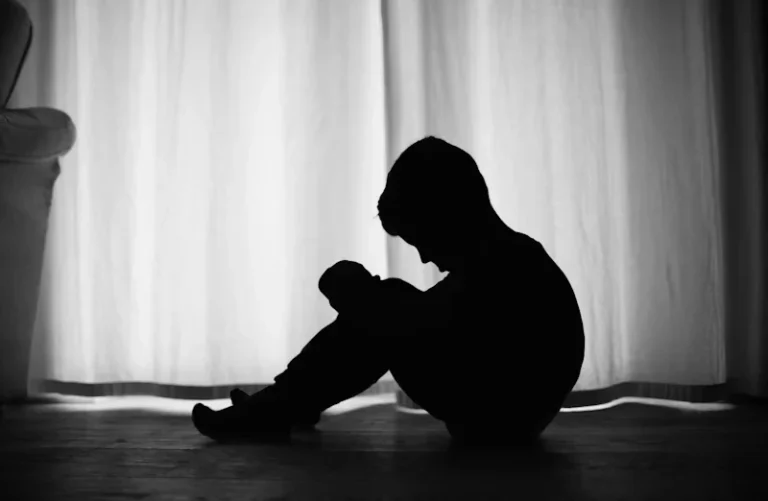 Kind zit verdrietig ineengedoken, symboliseert het ontstaan van hechtingsproblemen in de jeugd