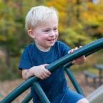 Jongetje speelt op een klimrek, leert vertrouwen op zijn lichaam.