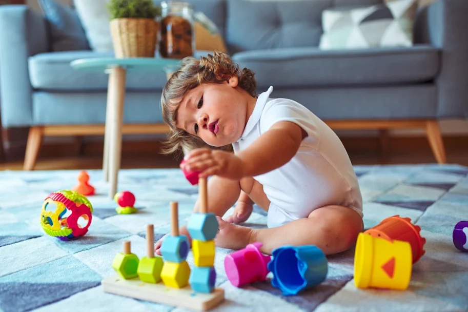 Peuter speelt geconcentreerd met blokken op kleed, illustreert ontdekken vanuit veilige basis