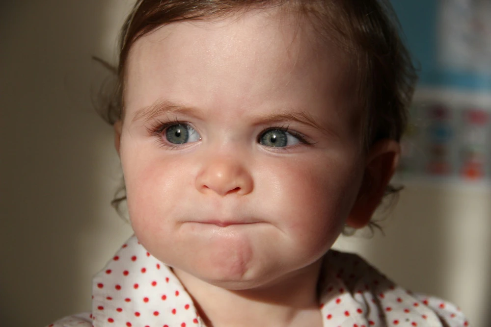 Peuter kijkt afwezig met samengeknepen lipjes alsof emoties worden ingeslikt, illustreert ontstaan onveilige hechting