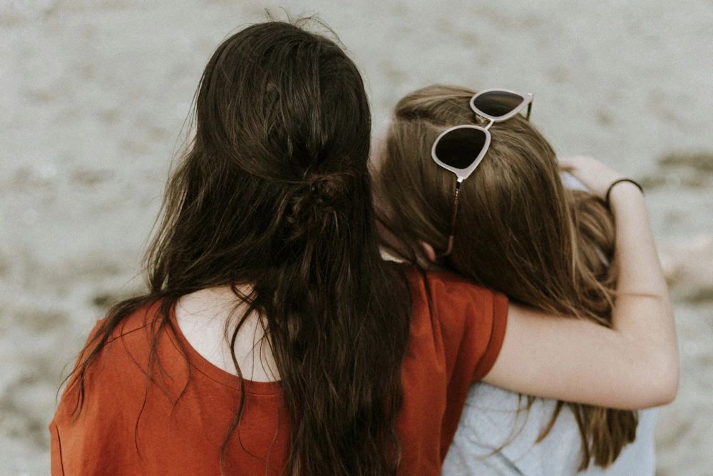 Vrouw biedt steun aan andere vrouw door arm om ander heen te leggen, illustreert belang van veilige relaties bij het verwerken van trauma