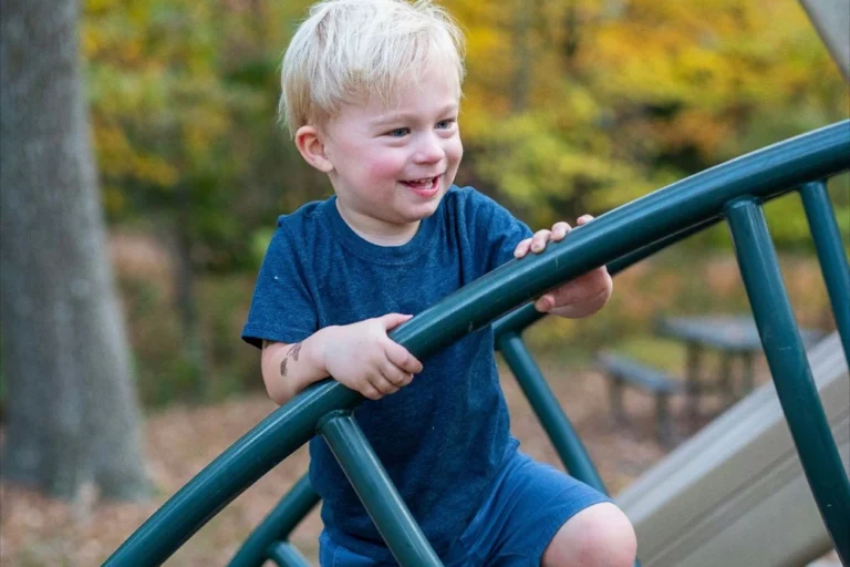 Lachend jongetje klimt geconcentreerd op klimrek, illustreert zelfvertrouwen ontwikkelen door uitdagingen aan te gaan