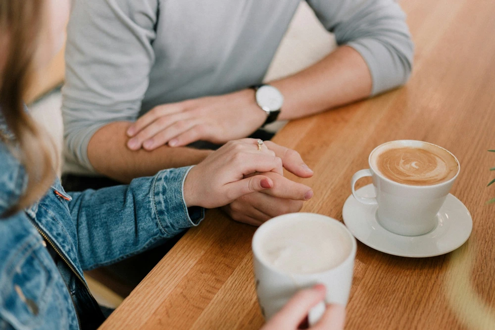 Een vrouw legt haar hand op de hand van een man, symboliseert hulp vragen en ontvangen bij veilige hechting