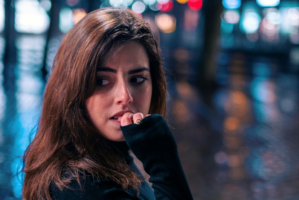 Vrouw kijkt angstig en bijt op haar nagels, symboliseert het angstige hechtingspatroon