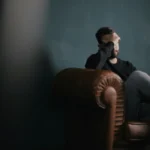 Man zit op bank met hand voor zijn ogen in emotionele crisis