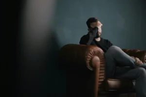 Man zit op bank met hand voor zijn ogen in emotionele crisis
