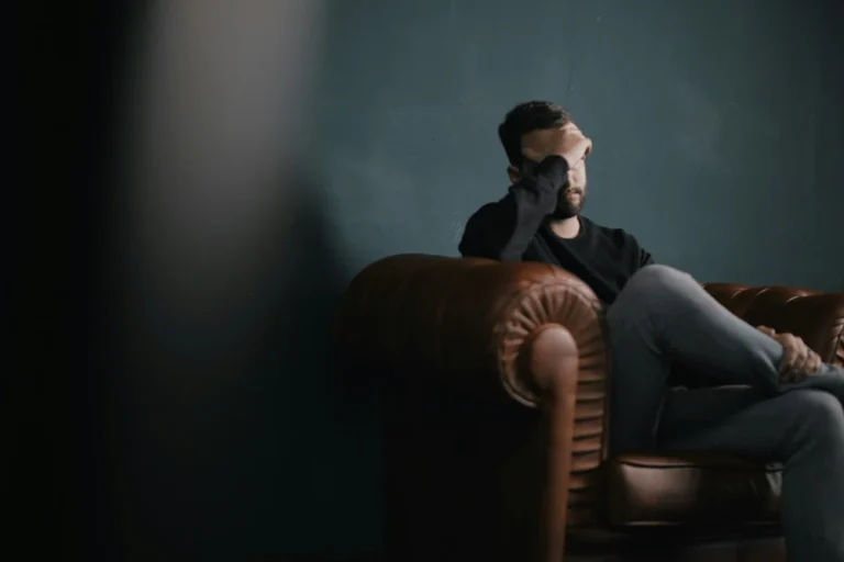 Man zit op bank met hand voor zijn ogen in emotionele crisis