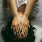Vrouw ligt op bed met haar handen voor haar ogen en voelt zich verliefd op haar therapeut