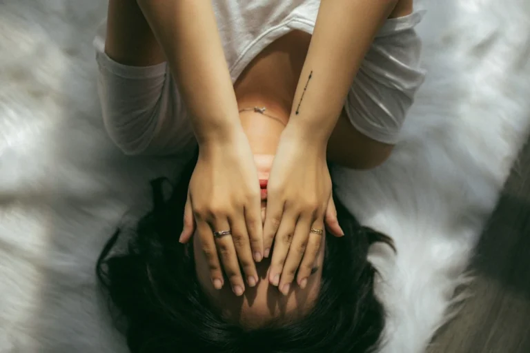 Vrouw ligt op bed met haar handen voor haar ogen en voelt zich verliefd op haar therapeut